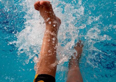 Low section of woman splashing water in swimming pool