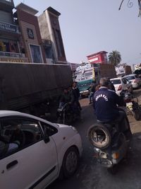 People riding motorcycle on road against buildings