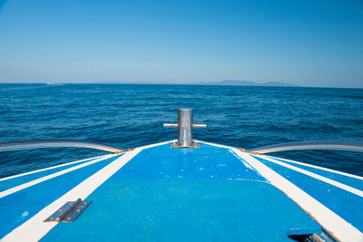 Boat sailing in sea against clear blue sky