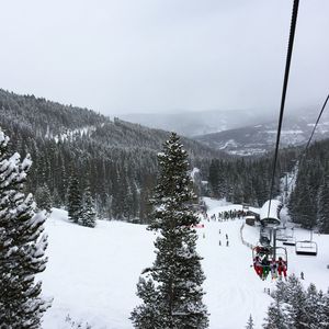 Ski lift over snowcapped mountains against clear sky during winter