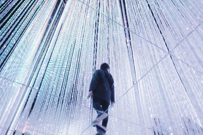Rear view of man walking on umbrella in city