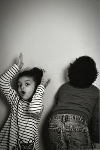 Rear view of boy standing against wall at home