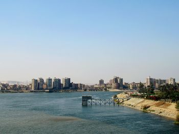 Sea and buildings against clear sky