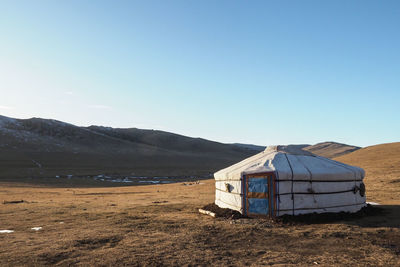 Built structure on field against clear blue sky