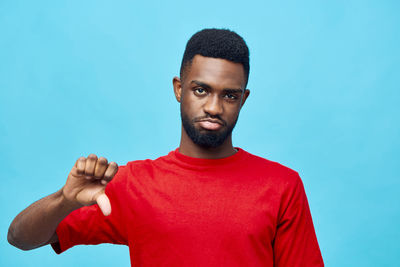 Portrait of young man standing against blue background