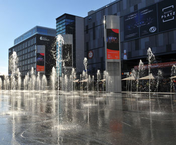 Water fountain by buildings in city during rainy season