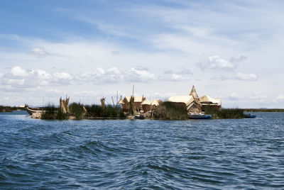 Buildings by sea against sky