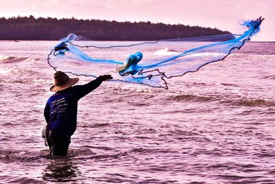 Full length of man fishing in sea against sky