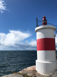 Lighthouse by sea against sky