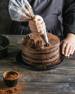 Midsection of man preparing cake on table