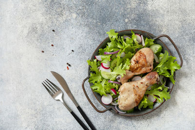 Baked chicken drumsticks and a green vegan salad made from a of green leaves and spring vegetables. 