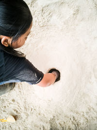 High angle view of girl putting hand on hole