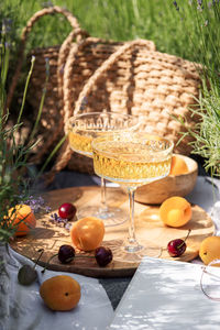 Summer picnic on a lavender field with champagne glasses, apricots and cherry berries