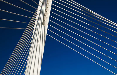 Low angle view of suspension bridge against clear blue sky