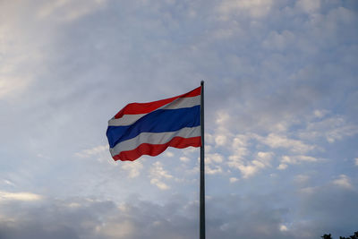 Low angle view of thai flags against sky