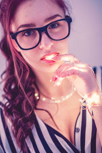 Young woman with illuminated string light against blue background