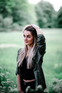 Portrait of young woman standing against plants