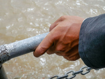 Close-up of hand holding railing against sea