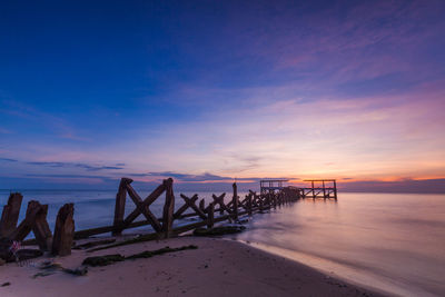 Pier on sea against sky during sunset