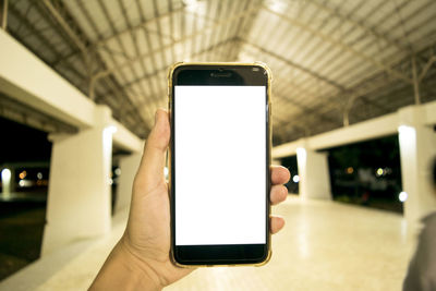 Close-up of human hand holding smart phone in built structure