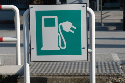 Green electric vehicle charging station sign, power plug and petrol pump