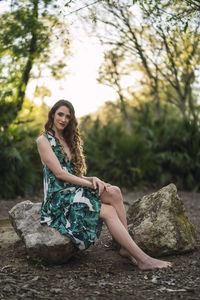 Portrait of young woman sitting on rock