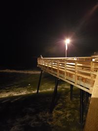 Pier over sea against sky at night