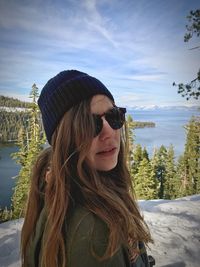 Close-up of young woman wearing sunglasses standing on mountain against sky