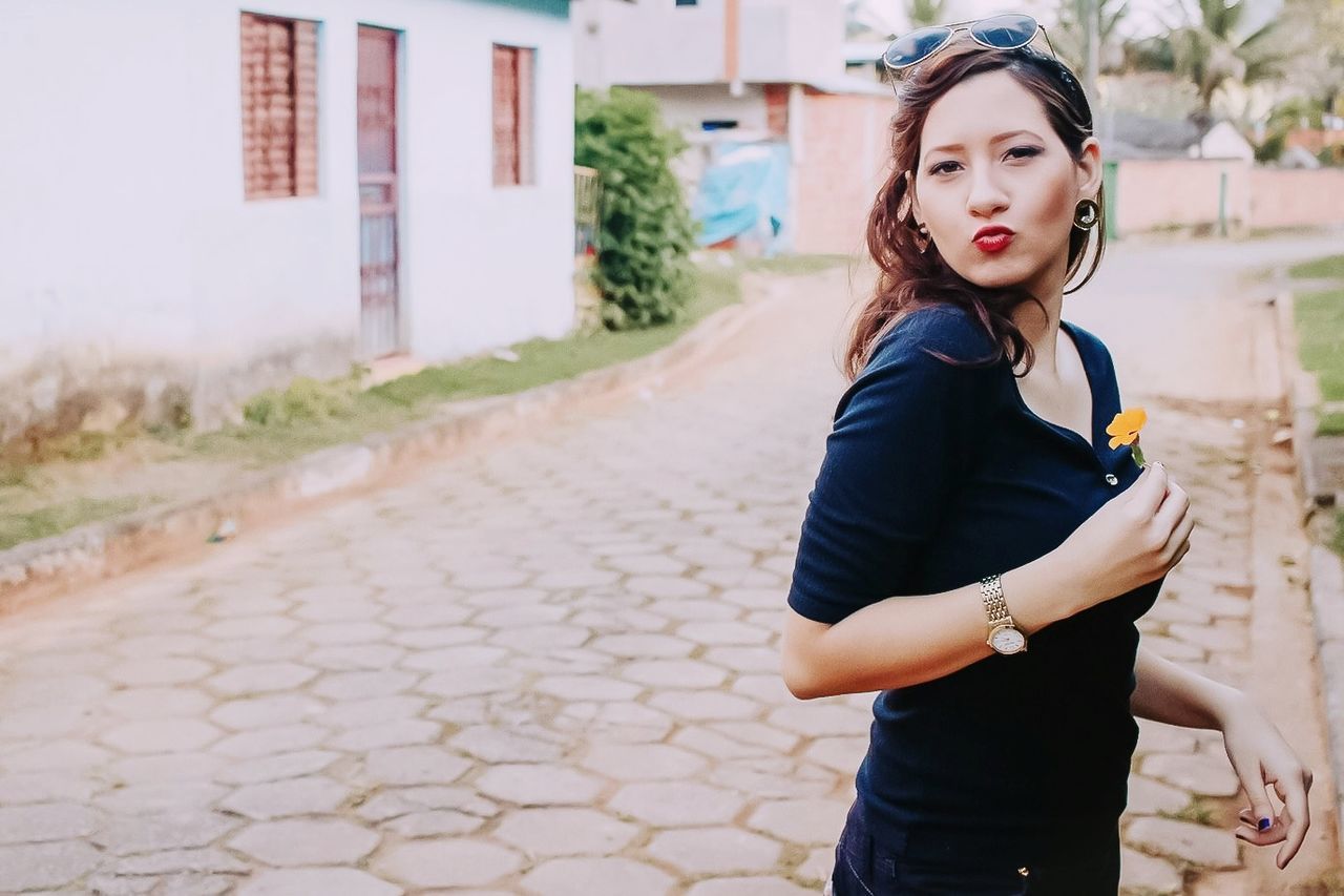 one person, standing, young adult, young women, looking at camera, focus on foreground, lifestyles, architecture, portrait, three quarter length, beauty, real people, casual clothing, day, city, leisure activity, built structure, beautiful woman, building exterior, fashion, outdoors, hairstyle, teenager