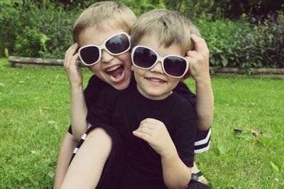 Portrait of happy boys wearing sunglasses on field