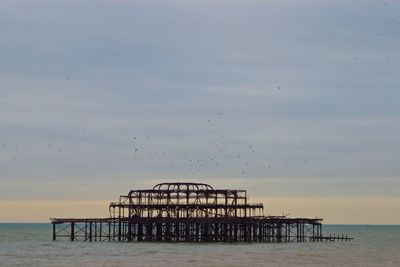 Abandoned pier on sea against clear sky