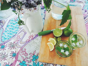 High angle view of mojito on cutting board by flower vase on table