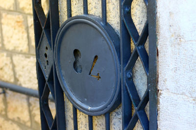 Close-up of rusty metal gate against wall