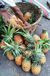 Cropped image of vendor keeping pineapples in basket at market