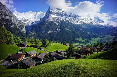 Scenic view of houses and mountains against cloudy sky