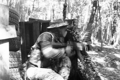 Side view of man climbing on tree trunk in forest