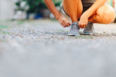 Low section of athlete tying shoelace on street