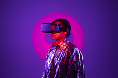 Spotlight falling on woman wearing virtual reality simulator against purple background