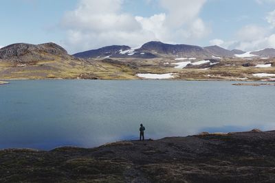 Rear view of man standing by mountains against sky