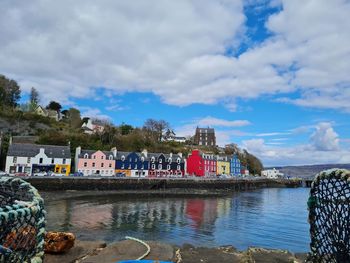 Buildings by river against sky