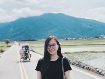 Portrait of smiling young woman against mountains