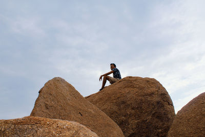 Low angle view of man on rock against sky