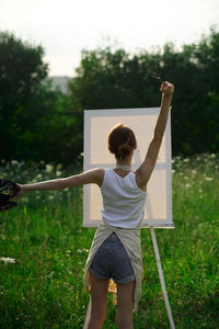 Rear view of woman standing on field