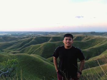 Portrait of smiling man standing on land against sky