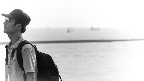 Young man in cap standing against sea