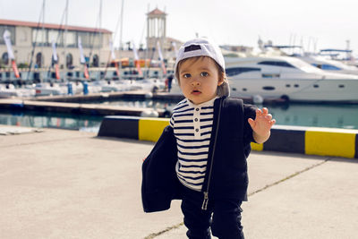 Little boy in a cap standing on the street in the seaport