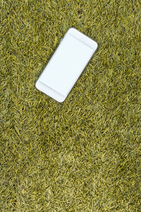 High angle view of mobile phone on grassy field
