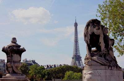 Lion statue against eiffel tower in city