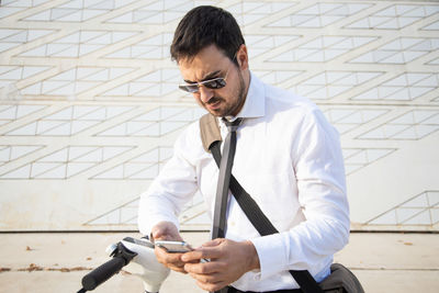 Businessman using smart phone standing outdoors