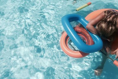 High angle view of woman with inflatable ring in swimming pool on sunny day